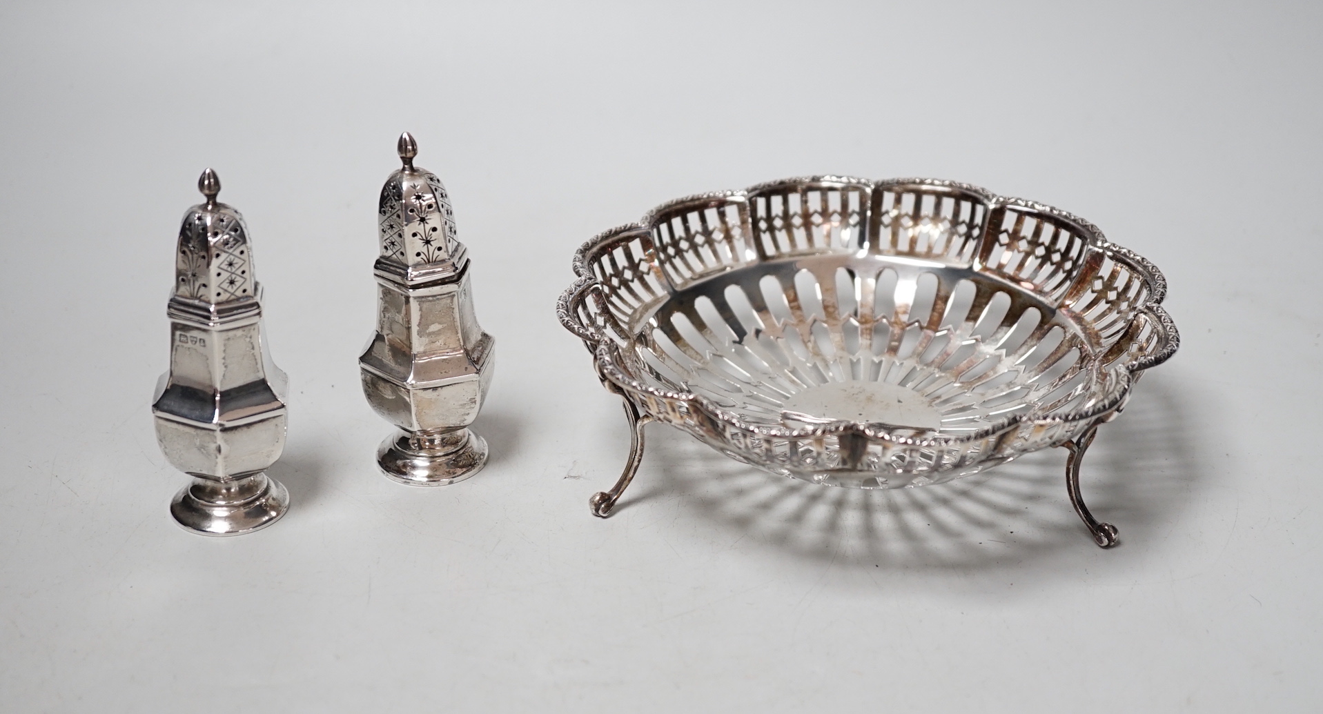 A George V pierced silver dish, Birmingham, 1912, 15.8cm and a pair of silver peppers, 5.9oz.